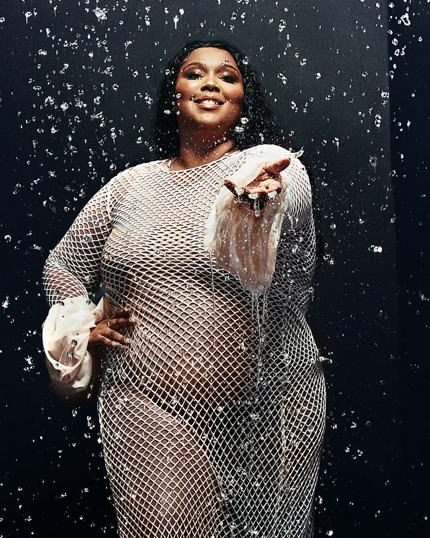 Lizzo in a white dress holding out her hand